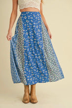 Load image into Gallery viewer, Woman wearing a blue floral skirt on a beige background
