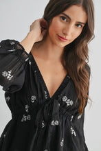 Load image into Gallery viewer, Woman wearing a black dress with floral embroidery on a plain background
