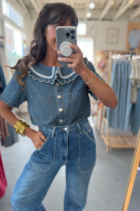 Woman taking a mirror selfie wearing a denim outfit in a store.