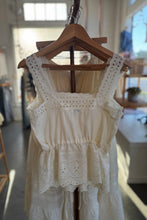 Load image into Gallery viewer, White lace dress on a wooden hanger in a blurred indoor setting