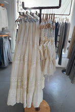 Load image into Gallery viewer, White lace dress hanging on a rack in a store setting