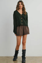 Load image into Gallery viewer, Woman wearing a green cardigan, plaid shorts, and black boots on a plain background