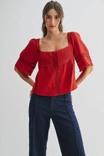 Load image into Gallery viewer, Woman wearing a red blouse with puffed sleeves and blue pants on a white background