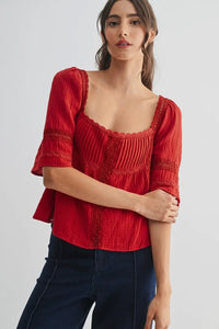Woman wearing a red blouse with lace details on a white background