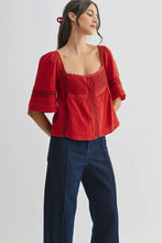 Load image into Gallery viewer, Woman wearing a red blouse and blue jeans on a white background