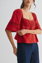 Load image into Gallery viewer, Woman wearing a red textured top and blue pants on a white background