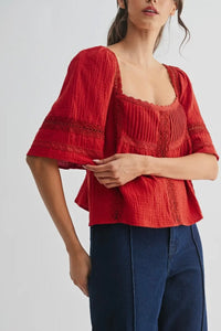 Woman wearing a red textured top and blue pants on a white background