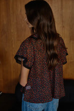 Load image into Gallery viewer, Person wearing a patterned shirt with short sleeves against a wooden wall.