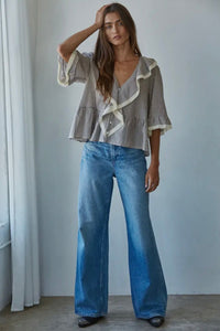 Woman wearing a striped blouse and blue jeans against a plain background