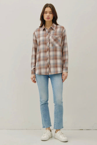 Woman wearing a plaid shirt and jeans on a plain background