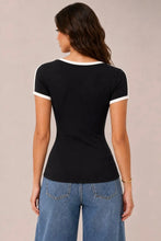 Load image into Gallery viewer, A woman shown from the back wearing a fitted black short-sleeve ringer T-shirt with white trim at the crew neck and sleeve cuffs, paired with blue jeans, against a plain light beige studio background.