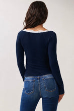 Load image into Gallery viewer, A woman viewed from the back wearing a navy blue long-sleeve top with a white lace trim at the neckline, paired with blue jeans, against a plain light gray background.