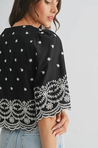Black top with white floral patterns on a plain background