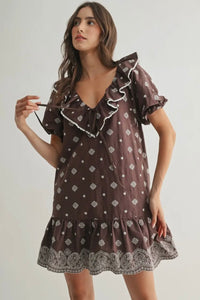 Woman wearing a brown patterned dress on a plain background