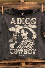 Load image into Gallery viewer, Black t-shirt with graphic design and text 'Adios Cowboy' on a wooden background