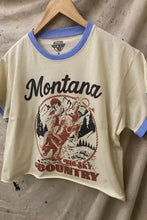 Load image into Gallery viewer, T-shirt with 'Montana Sky Country' design on a hanger against a textured wall.