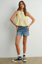 Load image into Gallery viewer, Woman wearing a yellow sleeveless top and denim shorts with black sneakers on a plain background