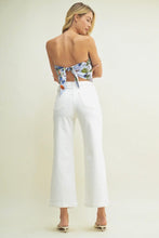 Load image into Gallery viewer, Woman wearing a floral top and white pants on a plain background