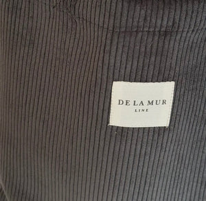 Close-up of dark gray corduroy fabric with a 'De La Mur' label.