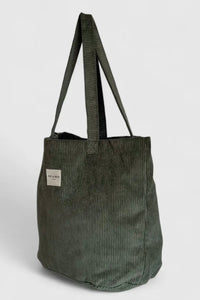 Green corduroy tote bag with a visible brand label on a light gray background