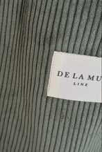 Load image into Gallery viewer, Close-up of a ribbed fabric texture with a &#39;De La Mura&#39; label.