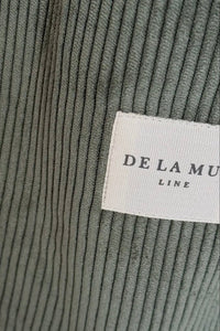Close-up of a ribbed fabric texture with a 'De La Mura' label.