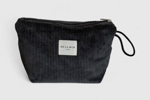 Black corduroy pouch with a visible brand label on a light gray background