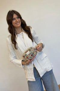 Woman holding a floral clutch against a plain background
