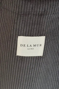 Close-up of dark gray corduroy fabric with a 'De La Mur' label.