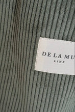 Load image into Gallery viewer, Close-up of ribbed fabric with a brand label on a gray background