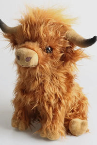 Plush toy of a brown Highland cow with black horns on a light gray background
