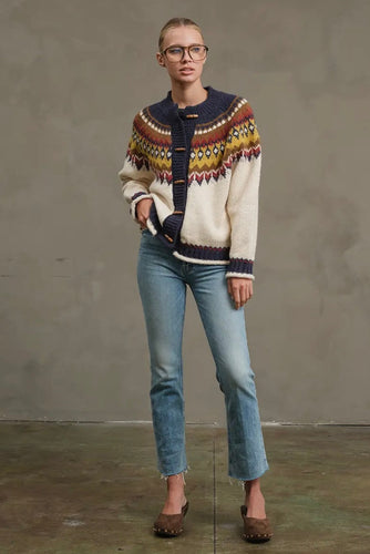 Person wearing a patterned sweater and jeans against a plain background