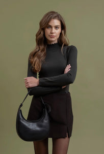 Woman holding a black handbag against a green background