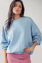 Load image into Gallery viewer, A woman wearing a light blue oversized crewneck sweatshirt and pink pants, photographed against a plain light gray studio background.