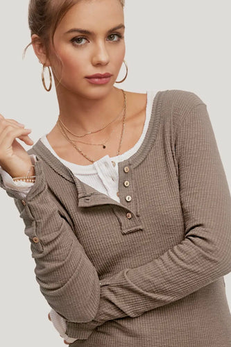 Woman wearing a brown textured cardigan over a white shirt on a plain background