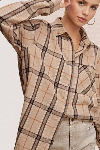 Woman wearing a beige and brown plaid shirt on a plain background