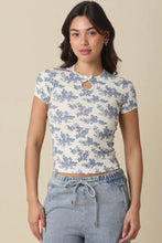Load image into Gallery viewer, Woman wearing a floral patterned top and gray pants on a beige background