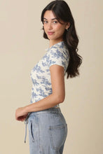 Load image into Gallery viewer, Woman wearing a floral top and jeans against a beige background
