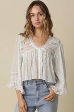 Load image into Gallery viewer, Woman wearing a white lace blouse and blue jeans against a beige background