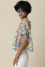 Load image into Gallery viewer, Person wearing a colorful floral blouse and sunglasses against a beige background
