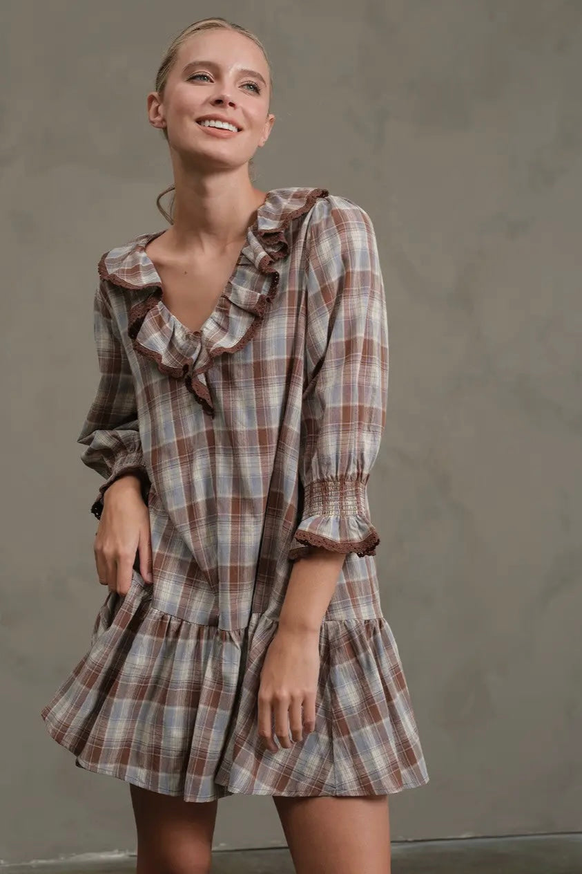 Woman wearing a plaid dress with ruffled details against a plain background