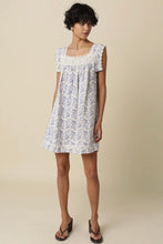 Load image into Gallery viewer, Woman wearing a floral dress against a beige background