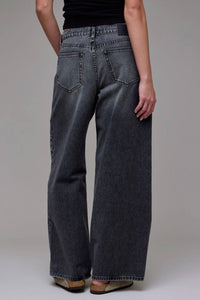 Person wearing dark blue jeans on a plain background