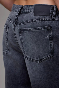 Close-up of dark blue jeans with a brand label on a gray background