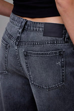 Load image into Gallery viewer, Close-up of gray jeans with a brand label on a neutral background