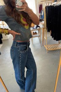 Person wearing a graphic t-shirt and blue jeans in a clothing store.