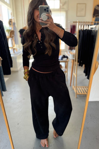 Person taking a mirror selfie wearing a black outfit in a clothing store.