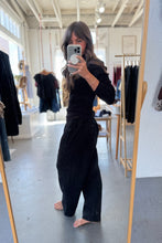 Load image into Gallery viewer, Person taking a mirror selfie wearing a black outfit in a clothing store.