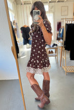 Load image into Gallery viewer, Person wearing a brown dress with white lace trim and brown boots in a clothing store.