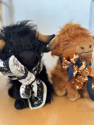 Two plush toys, one black and one brown with a bandana, on a light surface.